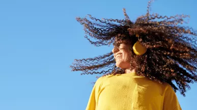 Момиче с жълт пуловер и слушалки